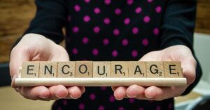 encourage spelled with scrabble tiles, representing the importance of praising staff